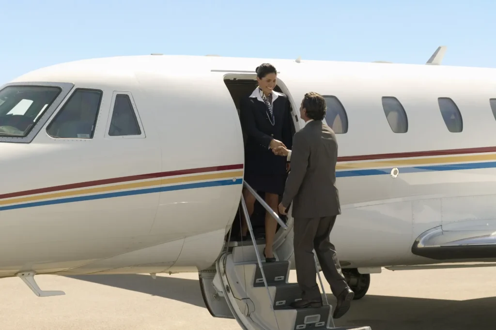 Passenger boarding a private jet with assistance from a flight attendant for a last-minute flight