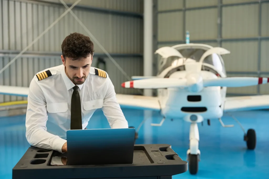 Pilot reviewing flight information beside an aircraft in a hangar.